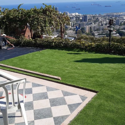 עובדים מתקינים דשא סינתטי בגינה עם כלים