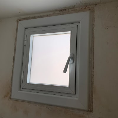 חלון אלומיניום עם ידית לבנה על קיר לבן