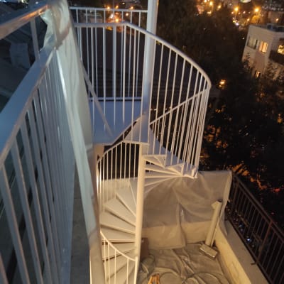 מדרגות לולייניות לבנות עם מעקה מתכת