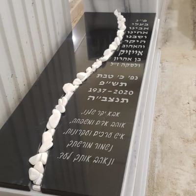 מצבה עם כיתוב בעברית ואבנים לבנות