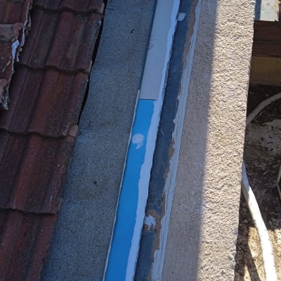 גג עם רעפים אדומים ותיקון איטום בצבע כחול