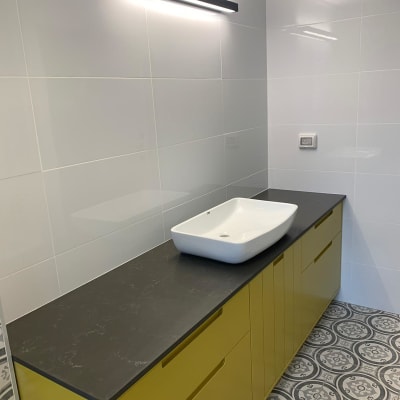 משטח שיש כהה עם כיור לבן בחדר אמבטיה