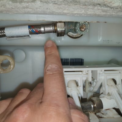 יד מצביעה על חיבור צינור מתכת במערכת אינסטלציה