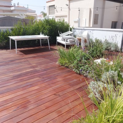 דק עץ עם צמחייה ירוקה ושולחן לבן