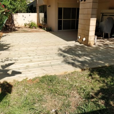 דק עץ חדש בגינה ליד קיר בית