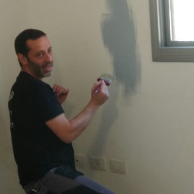 אדם צובע קיר בצבע אפור עם מברשת