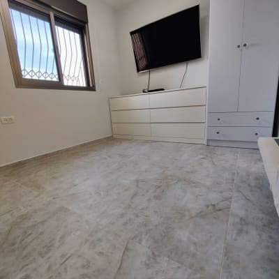 רצפת אריחים חדשה בחדר עם ארון וטלוויזיה