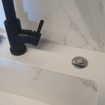 ברז שחור וכפתור נירוסטה בכיור לבן