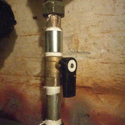 צינור מתכת עם ברז שחור על רקע קיר