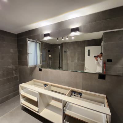 מראה גדולה על קיר חדר אמבטיה עם תאורה