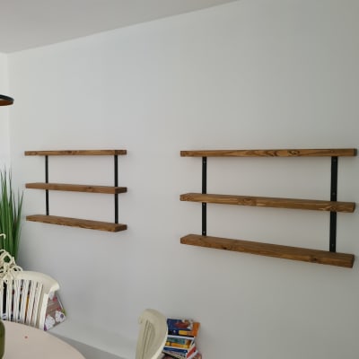 מדפים מעץ מותקנים על קיר עם תומכים שחורים