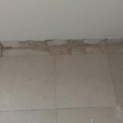 קיר עם טיח מתקלף מעל רצפה מרוצפת