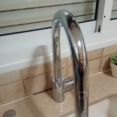 ברז מטבח כסוף על משטח שיש ליד חלון