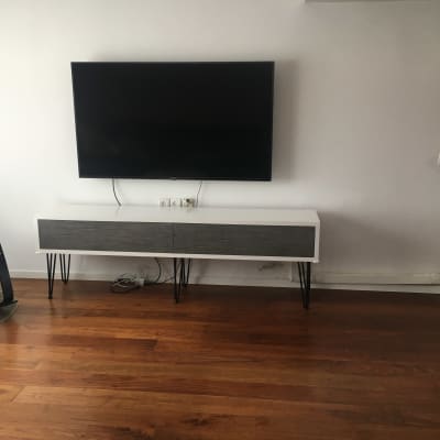 טלוויזיה תלויה על קיר מעל שידה מעץ