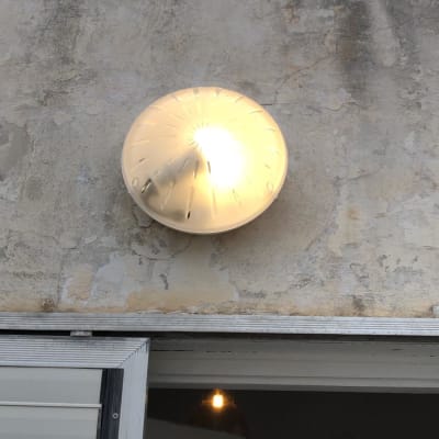 מנורת קיר עגולה דולקת על קיר חיצוני