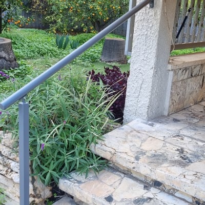מעקה מתכת אפור ליד מדרגות אבן בגינה