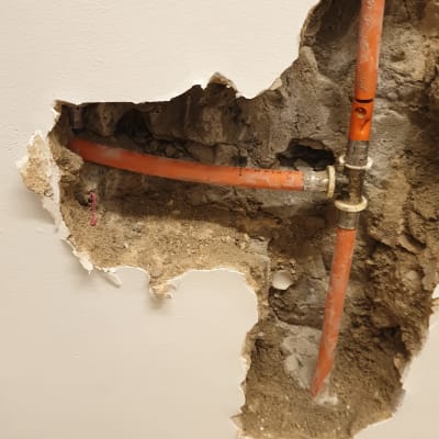 צינור כתום בקיר שבור עם חיבור מתכת