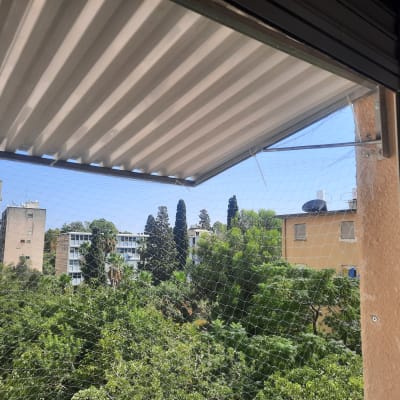 סוכך מתכת מותקן מעל חלון עם רשת הגנה