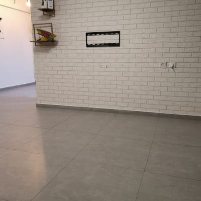 קיר לבנים עם מתקן לטלוויזיה, רצפת אריחים אפורה