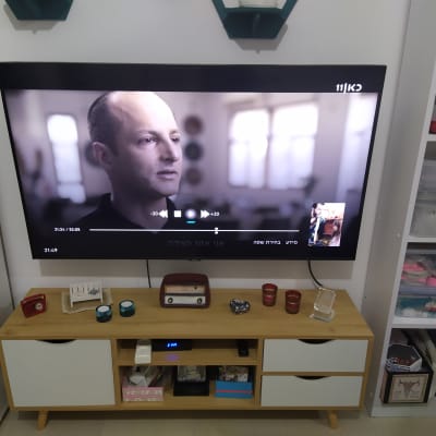 טלוויזיה תלויה על הקיר עם מדף מתחתיה