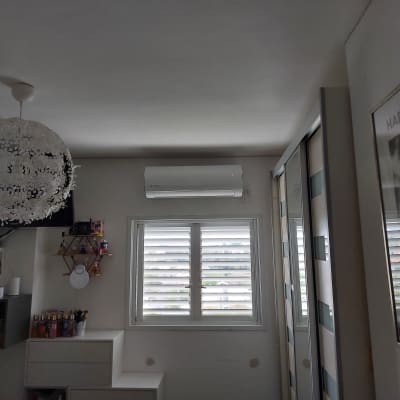 מזגן מותקן על קיר מעל חלון עם תריסים