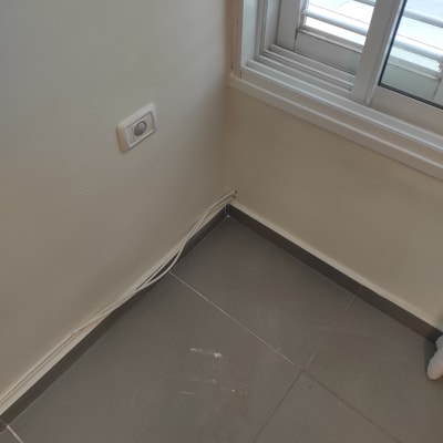 קיר עם שקע חשמל וחוטים חשופים ליד חלון