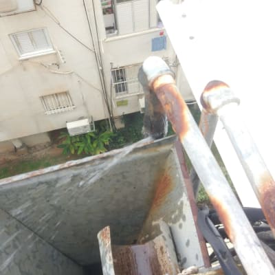 צינורות חלודים עם מים זורמים מגג בניין