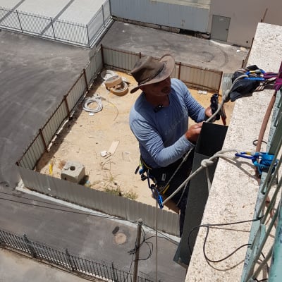 אדם עובד על גג עם חבלים וציוד בטיחות