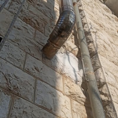 צינור מתכת אטום על קיר אבן חיצוני