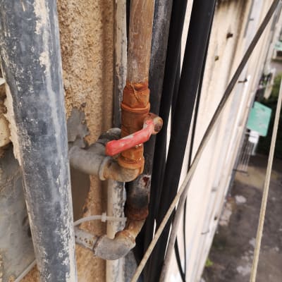 צינור חלוד עם ברז אדום על קיר חיצוני