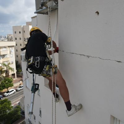 אדם על חבל אוטם סדק בקיר חיצוני