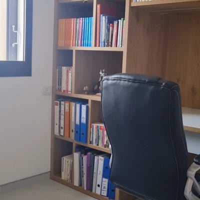 מדפי ספרים עם קלסרים צבעוניים וכיסא משרדי שחור