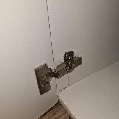 ציר מתכת מותקן על דלת ארון לבנה