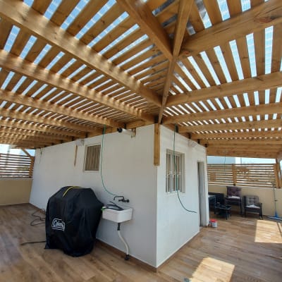 פרגולה מעץ עם כיור וברז על מרפסת