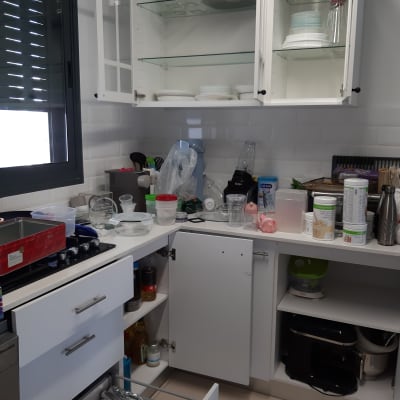 מטבח עם ארונות פתוחים, כלים ומכשירי חשמל על השיש