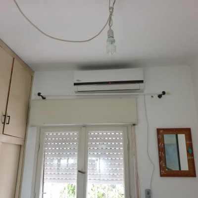 מזגן מותקן על קיר מעל חלון עם תריסים