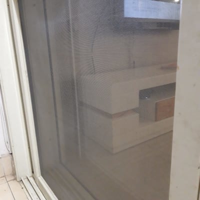 תריסים לבנים עם רשת שקופה על מסילה