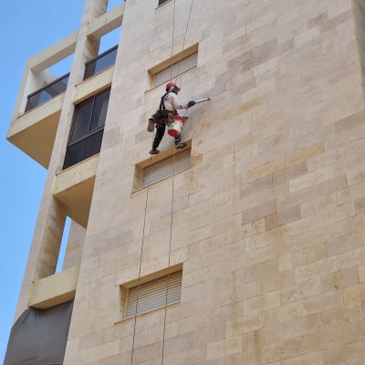 אדם עם ציוד סנפלינג עובד על קיר בניין