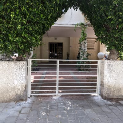 שער מתכת לבן בין קירות בטון וגדר חיה