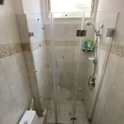 מקלחון זכוכית עם ראש מקלחת ומדף מוצרים