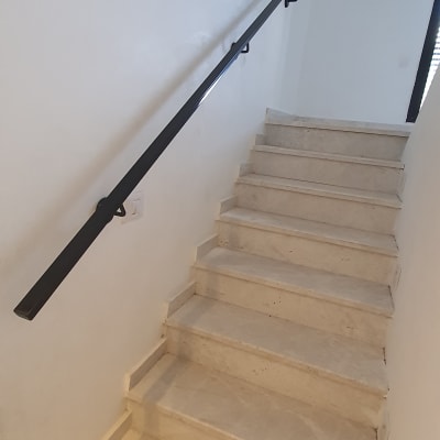 מעקה מתכת שחור לאורך גרם מדרגות לבן