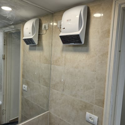 מייבש ידיים מותקן על קיר אריחים בחדר אמבטיה