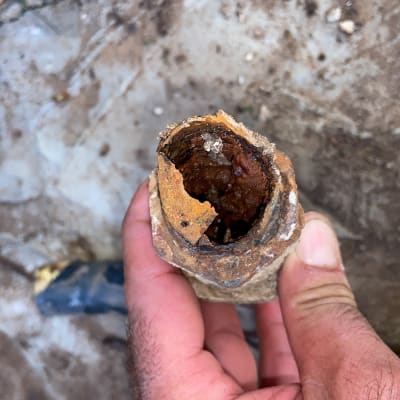 צינור חלוד עם חלודה פנימית ביד של אדם