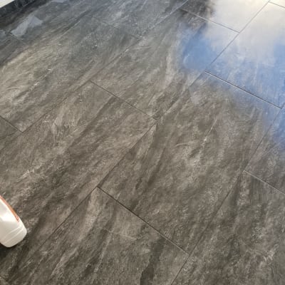 רצפת אריחים אפורה עם בקבוק חומר ניקוי בפינה