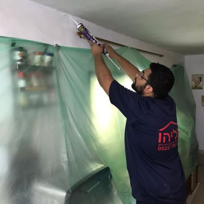 אדם אוטם תקרה עם אקדח סיליקון