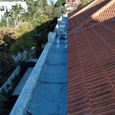 גג עם יריעות איטום ליד רעפים אדומים