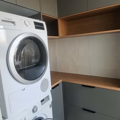 מכונת כביסה ומייבש בחדר כביסה עם ארונות עץ