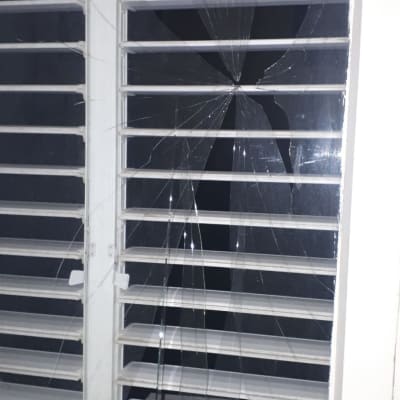 זכוכית שבורה בחלון עם תריסים לבנים