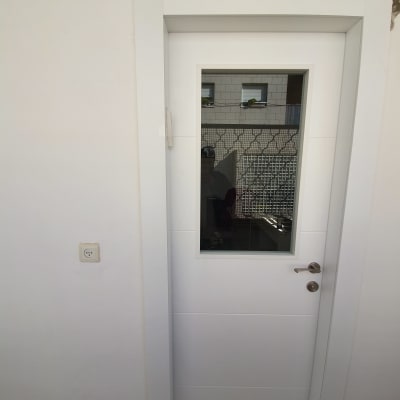 דלת לבנה עם חלון זכוכית וידית מתכת