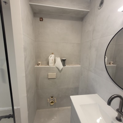 בקבוק חומר ניקוי וכוסות נייר על מדף בחדר אמבטיה